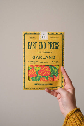 Verpackung der Früchte-Girlande von East End Press in der Hand gehalten