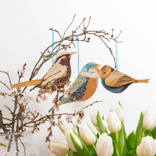 Drei Papiervögel von East End Press an einem Zweig über weißen Tulpen