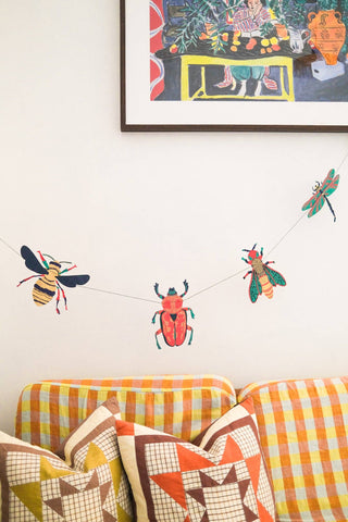 Insekten-Girlande von East End Press über einem karierten Sofa