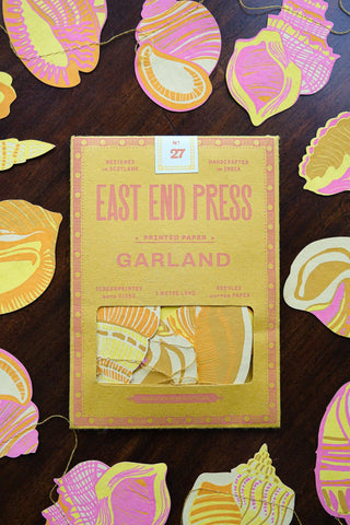 Verpackung der Muschel-Girlande von East End Press zwischen einzelnen Papiermuscheln