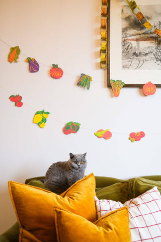 Früchte-Girlande von East End Press über einem Sofa mit Katze