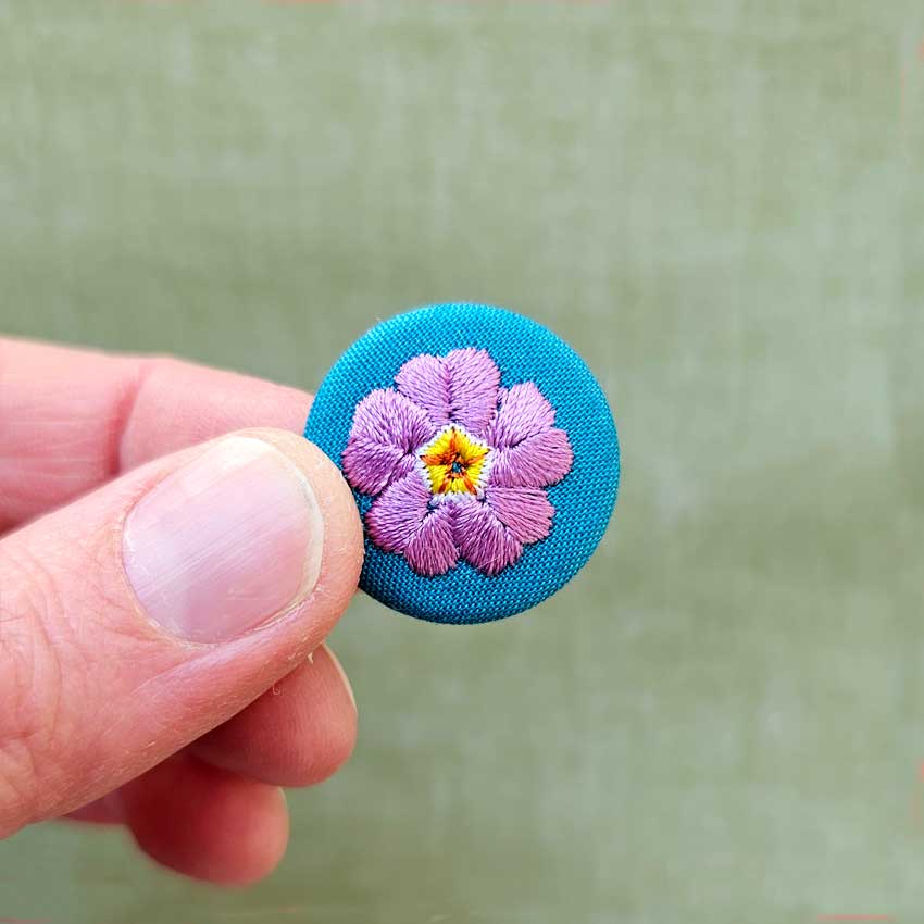 une hirondelle fait le printemps. - gestickte Brosche "Primeln" lila